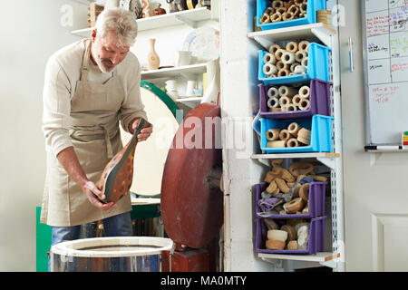 Homme mature dans un atelier de poterie Vase en four de cuisson Banque D'Images