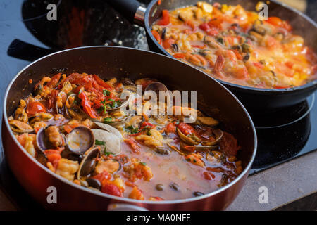 Close-up de deux poêles à frire avec plat de fruits de mer cuits dans la sauce tomate. Compotée de palourdes fraîches, crevettes, moules et calamars, base de pâtes italiennes Banque D'Images