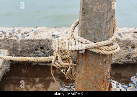 Vieux bateau de pêche corde avec un Nœud attaché autour de l'ancien poste de béton Banque D'Images