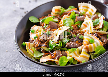 Coeurs de poulet avec des carottes dans une sauce aigre-douce avec des pâtes farfalle. Salade saine Banque D'Images