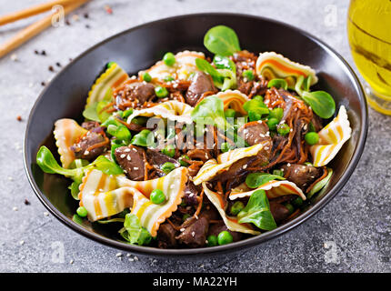 Coeurs de poulet avec des carottes dans une sauce aigre-douce avec des pâtes farfalle. Salade saine Banque D'Images