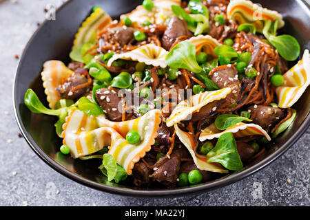 Coeurs de poulet avec des carottes dans une sauce aigre-douce avec des pâtes farfalle. Salade saine Banque D'Images