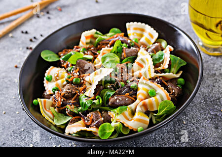 Coeurs de poulet avec des carottes dans une sauce aigre-douce avec des pâtes farfalle. Salade saine Banque D'Images
