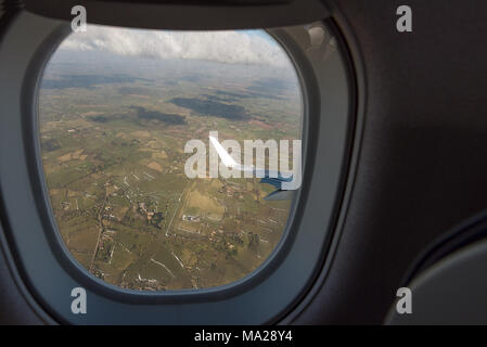 Voir par la fenêtre d'un avion de passagers d'avion volant à basse altitude au-dessus des champs verts de la campagne anglaise. Banque D'Images