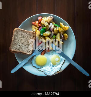 Oeufs au plat avec des toasts croustillants et ragoût de légumes dans une assiette. La vue du sommet. Un petit-déjeuner végétarien. Le processus d'alimentation. Banque D'Images