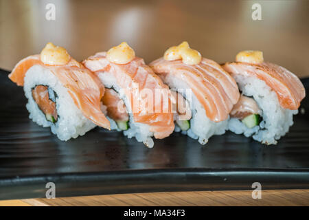 Pavé de saumon sushi roll, nourriture japonaise sur style plat de céramique noire Banque D'Images