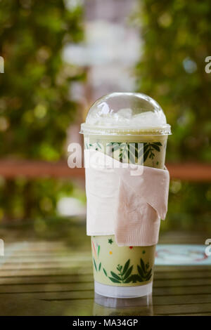 Matcha latte dans la tasse en plastique avec couvercle dans la nature Banque D'Images