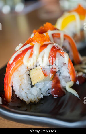 Sushi roll stick de crabe avec sauce aux fraises, nourriture japonaise sur style plat de céramique noire Banque D'Images