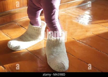 Petite fille essayant des chaussettes de laine du papa à la maison Banque D'Images