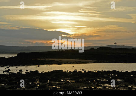 St Cuthbert's Isle, Northumberland au coucher du soleil et avec la croix illustrée en silhouette Banque D'Images