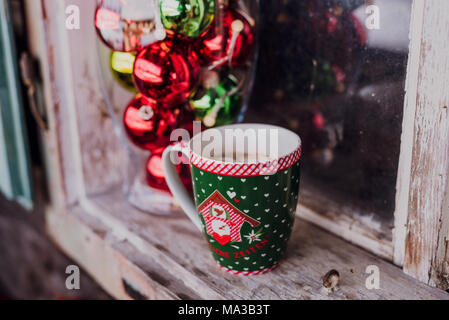 La fenêtre, décorations,vase en verre rempli de boules de noël et une tasse à café, Banque D'Images