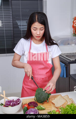 Femme à l'aide de couteau pour couper le brocoli dans la cuisine chambre à la maison Banque D'Images