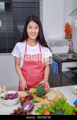 Femme à l'aide de couteau pour couper le brocoli dans la cuisine chambre à la maison Banque D'Images