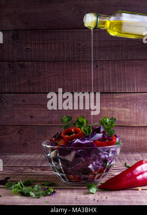 Salade de chou rouge et poivrons rouges, assaisonnée de jus de citron et l'huile d'olive dans une table en bois Banque D'Images