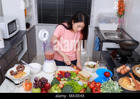 Jeune femme faisant des smoothies avec le mélangeur dans la cuisine