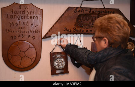 26 mars 2018, l'Allemagne, Wunstorf/Langenberg : Annelie Lausch, membre fondateur de la société coopérative de la maison communautaire 'Zum Schanko' pins un fanion de football sur le mur. Avec la fondation de la société coopérative les initiateurs l'espoir de sauver la maison communitiy. Photo : Carmen Jaspersen/dpa Banque D'Images