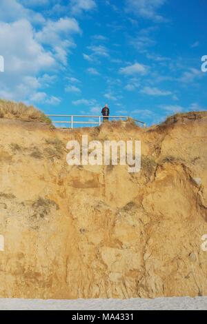 Un homme debout en haut d'une dune de sable glissement de terrain sur l'île de Sylt, Schleswig-Holstein Banque D'Images