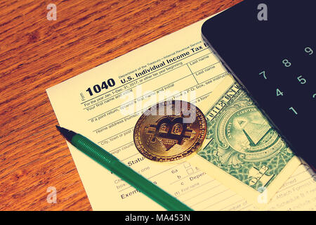 Jour de l'impôt. L'impôt sur le formulaire 1040, stylo vert, noir smartphone avec calculatrice, dollar et bitcoin est sur une table en bois. Banque D'Images