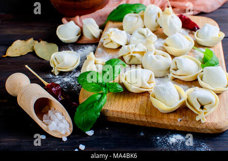Les beignets de viande faits maison sur la carte sur un fond sombre, farinés, de piment, sel, basilic, Fédération des pelmeni traditionnelle avec de la viande, Banque D'Images