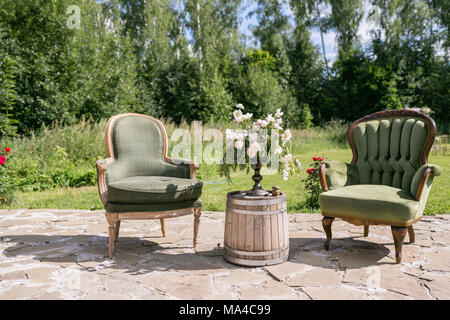 Chaises et table en bois vintage avec décoration de fleurs jardin en plein air. Banque D'Images