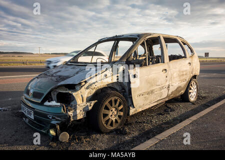 Abandonnés endommagé brûlé voiture reste sur le côté de la route, UK Banque D'Images