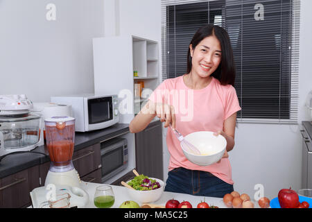 La cuisine et femme en fouettant les oeufs dans un bol dans la cuisine prix Banque D'Images