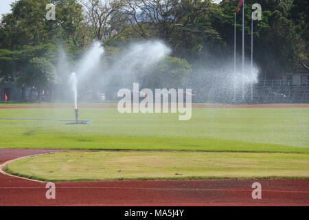 Casiers pulvériser de l'eau sur l'herbe au terrain de football Banque D'Images