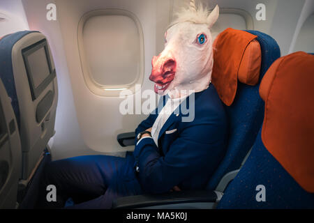 Étrange passager en costume élégant siège seul à l'intérieur de l'avion et prêt à décoller. Voyageur inhabituel dans l'air voyage. Banque D'Images