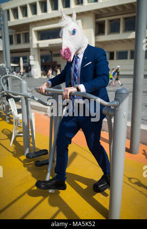 Funny man in suit et masque n'exerce dans le sport sport terre près de la promenade. Sportsman inhabituelle des muscles des pompes. Unicorn élégant est engagé en fitness Banque D'Images