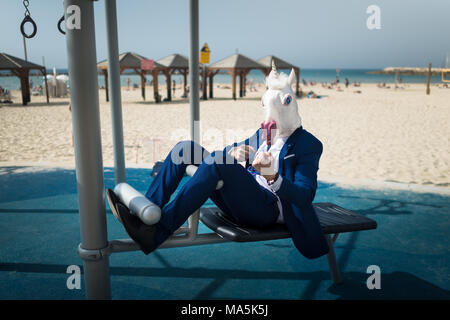 Rare man in suit et masque cheval faire du sport près de plage. Freaky guy muscles pompes et montre la force. Remise en forme en plein air unicorn drôle Banque D'Images