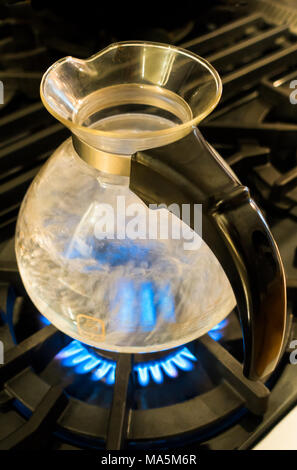 D'ébullition de l'eau dans une bouilloire sifflante en verre par Medelco sur une cuisinière Banque D'Images