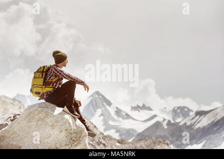 L'homme voyageur backpacker se trouve rocher sur la montagne Banque D'Images