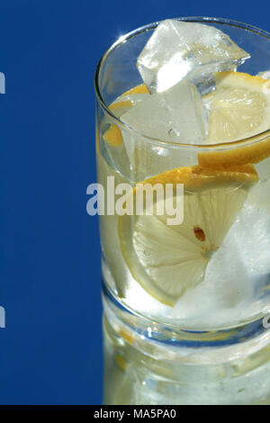 Verre d'eau avec du citron et des glaçons sur fond bleu Banque D'Images