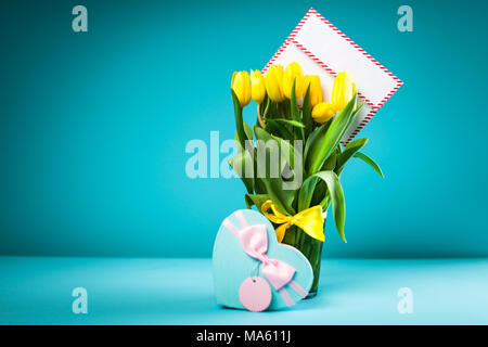 Tulipes dans un vase jaune sur fond bleu Banque D'Images