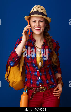 La recherche de lieux d'inspiration. smiling fit traveller femme dans une chemise à carreaux en conversation sur un téléphone mobile sur fond bleu Banque D'Images