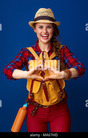 La recherche de lieux d'inspiration. smiling young woman voyageur avec sac à dos en forme de cœur montrant mains isolé sur blue Banque D'Images