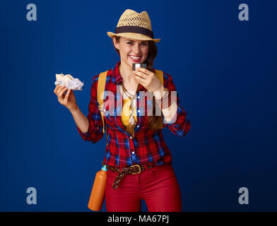 La recherche de lieux d'inspiration. bonne femme jeune voyageur dans un plaid shirt avoir pause-repas contre fond bleu Banque D'Images