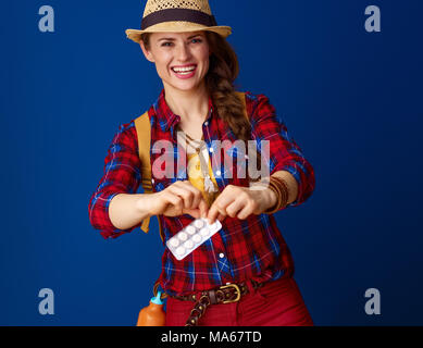 La recherche de lieux d'inspiration. Happy Adventure'Femme avec sac à dos prend un comprimé de l'emballage isolé sur fond bleu Banque D'Images