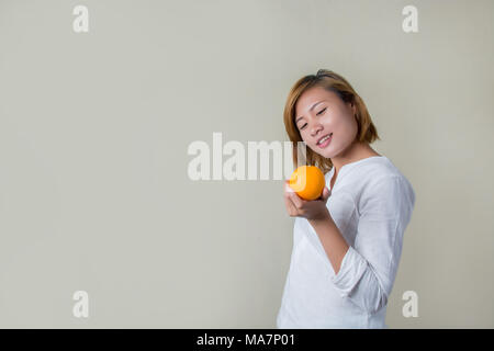 Beautiful young asian woman holding orange sur fond blanc Banque D'Images