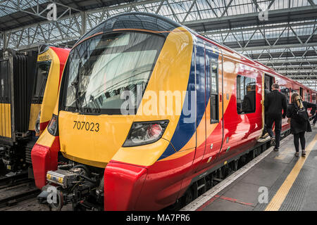 Les passagers se précipitent pour une locomotive Desiro City Class 707 du South Western Railway, construite par Siemens, avec une Class 455 à l'arrière-plan. Banque D'Images