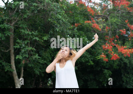 Vie des femmes concept : Beautiful young asian woman stretching et de bâiller à l'air frais dans le vert du parc. Banque D'Images