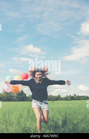 Jeune belle asian woman holding balloon sur prairie verte l'exécution de profiter de l'air frais Banque D'Images