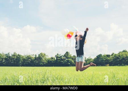 Jeune belle asian woman holding balloon sur prairie verte courir et sauter profiter de l'air frais Banque D'Images
