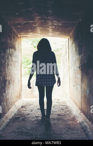 Silhouette de femme hippie à pied dans le tunnel. La lumière au bout de tunnel Banque D'Images