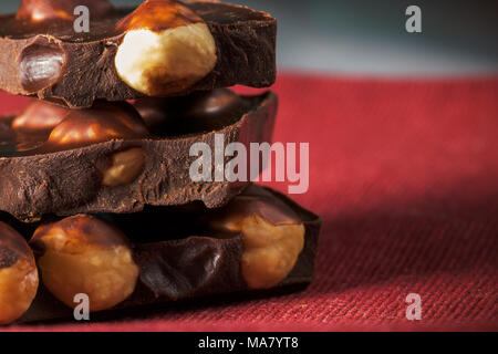 Tranches de chocolat noir naturel avec les noisettes sur une serviette rouge. Close-up macro-vision Banque D'Images