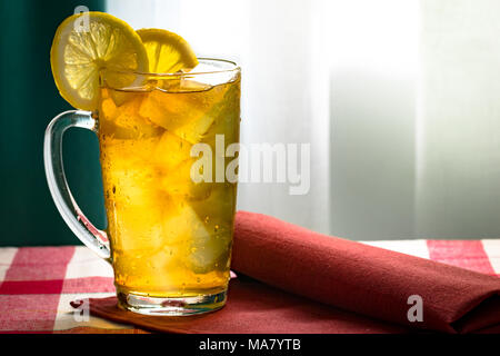 Thé froid au citron et des glaçons dans un verre haut transparent tasse sur une serviette rouge Banque D'Images