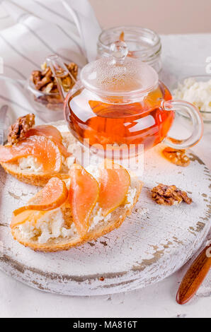 Petit déjeuner avec des sandwichs. plateau de fromage ricotta et poires confiture. Tasse de thé et théière en verre. Vue de dessus, copy space Banque D'Images