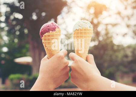 Woman's hands holding melting ice cream cornet gaufré dans les mains sur la lumière d'été nature background Banque D'Images