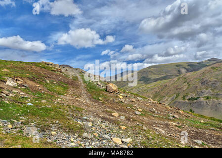 Rocky la saleté route raide entre les pierres dans les montagnes sur le fond bleu du ciel et nuages Banque D'Images