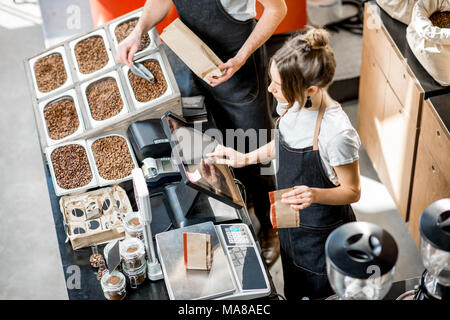 Deux vendeurs en uniforme et d'un poids de remplissage de sacs de café dans le magasin de café. Vue de dessus Banque D'Images